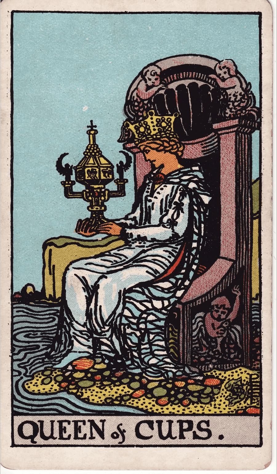 The Queen of Cups from the 1909 Rider-Waite-Smith deck: a queen sits on a throne decorated with sea creatures at the edge of the water, gazing at an ornate closed cup with angel handles