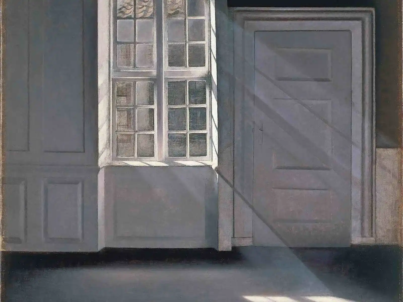 An empty grey room with a tall window and a closed door, crossed by quiet diagonal beams of sunlight