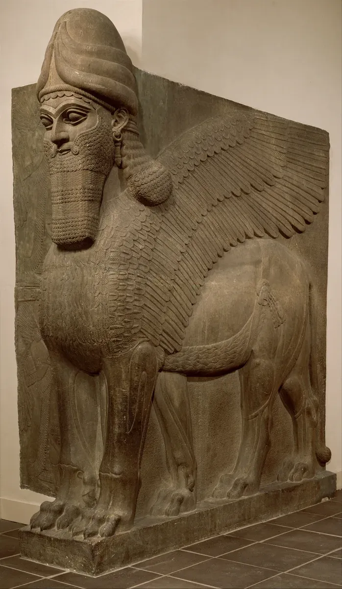 Colossal stone guardian with a lion body, wings and a bearded human head wearing a horned crown