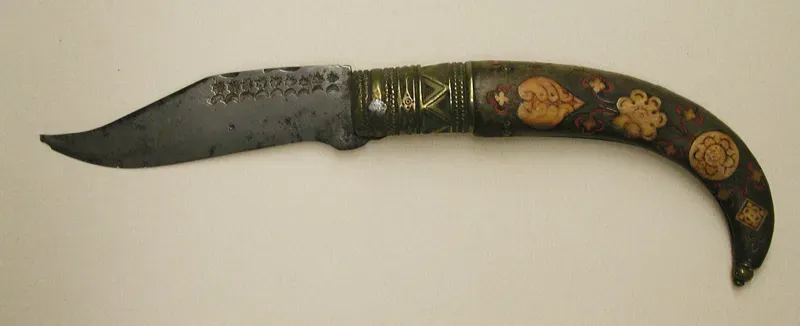 A folding knife with a curved steel blade and a dark handle decorated with small painted dots