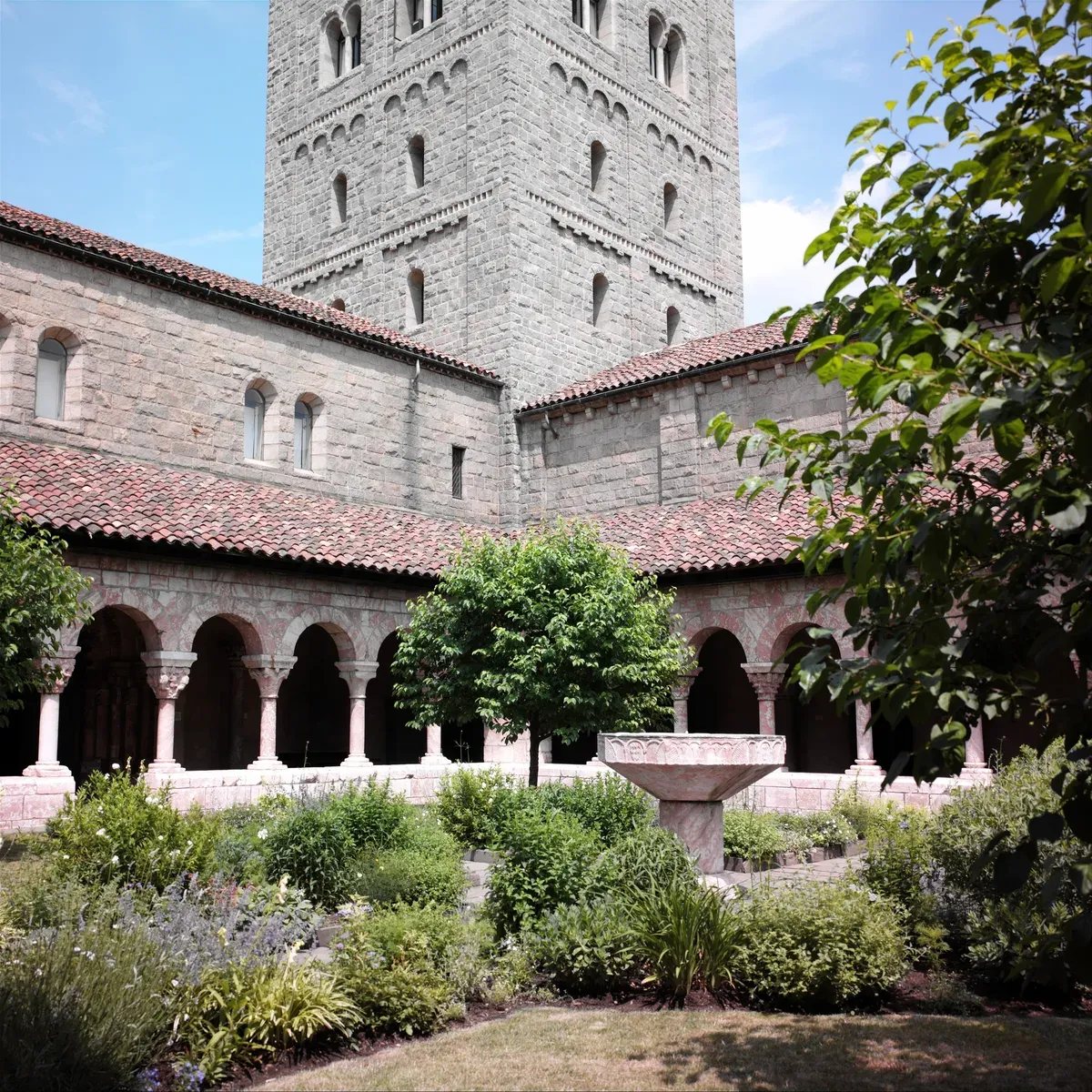 A medieval cloister garden surrounded by arcades of round arches on slender columns with carved capitals