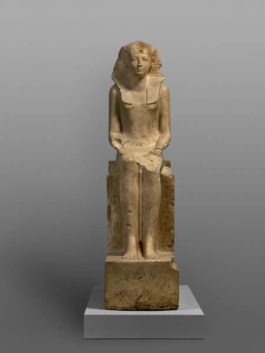Seated limestone statue of Hatshepsut in a royal headcloth, hands on her knees