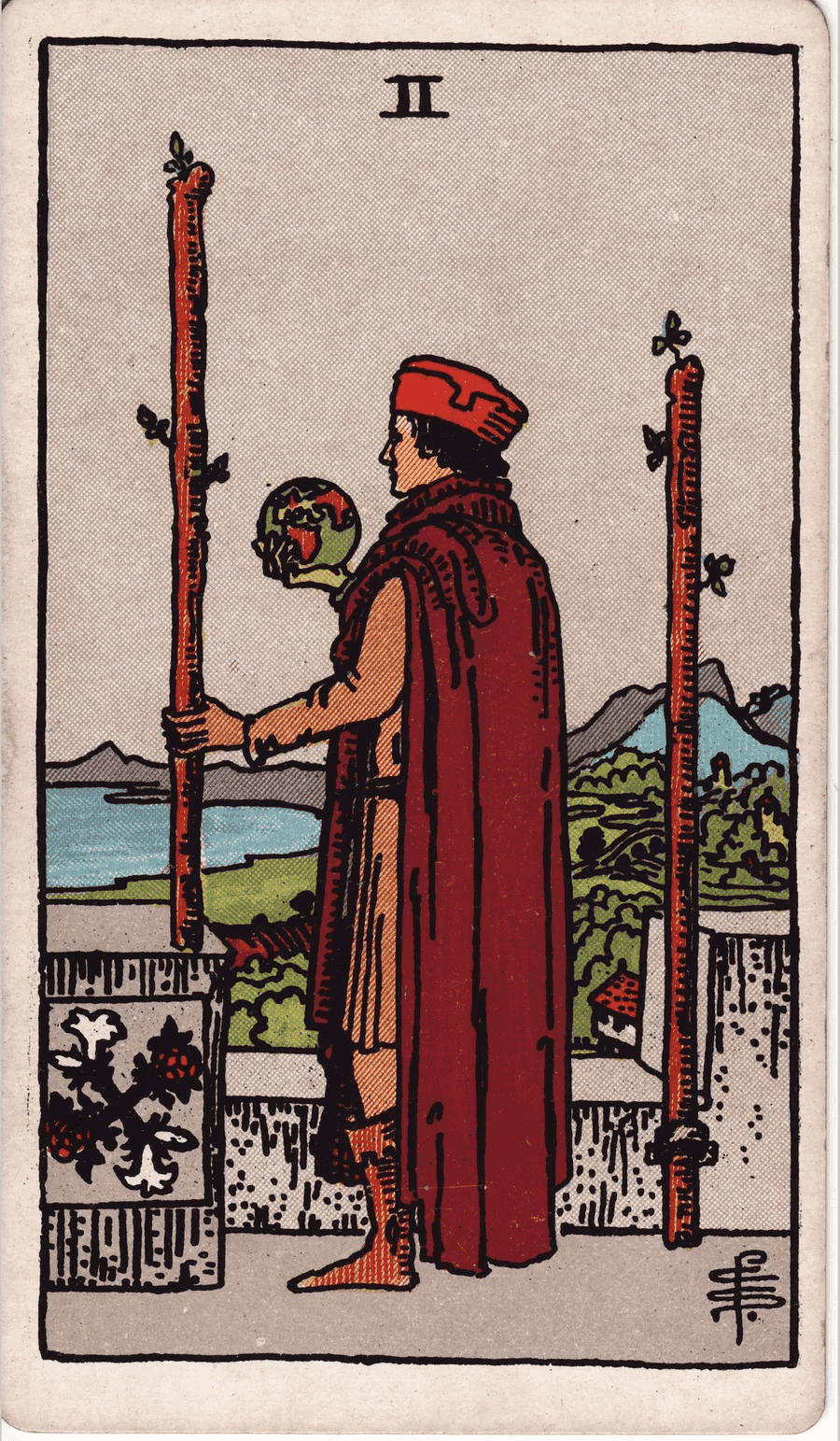 The Two of Wands from the 1909 Rider-Waite-Smith deck: a man in a red cloak stands on a castle wall holding a small globe and a wand, looking out over land and sea, with a second wand fixed to the wall